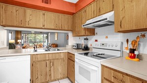 A modern kitchen with wooden cabinets, a white countertop, a built-in oven, and a stove. - Upstay Golfer's Retreat w Patio at Ventura Resort (Orlando)