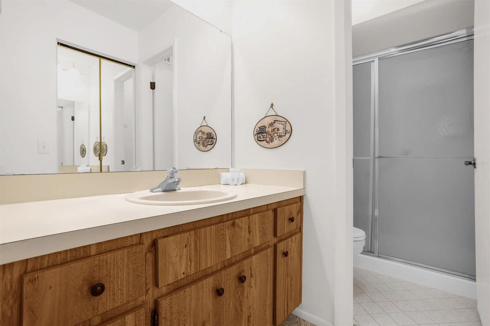 Une salle de bain moderne avec un meuble-lavabo en bois, un grand miroir et deux assiettes décoratives fixées au mur.
