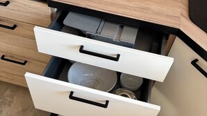 Ett kök med en inbyggd diskmaskin, vita skåp och en bänkskiva i trä.