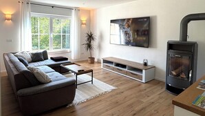Ett modernt vardagsrum med en soffa, en tv, en öppen spis och ett stort fönster.