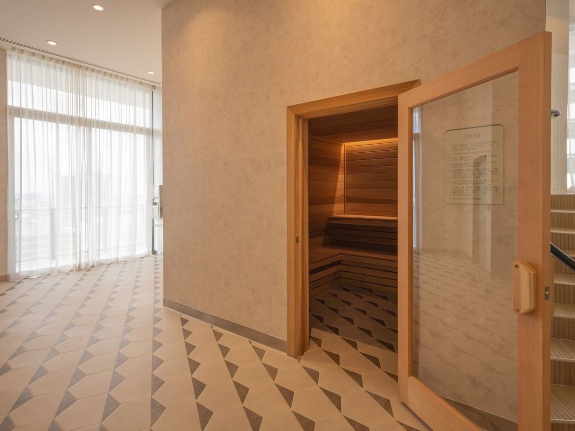 Une pièce avec un sol à motifs, un banc en bois et une porte en verre sur laquelle est apposée une pancarte.