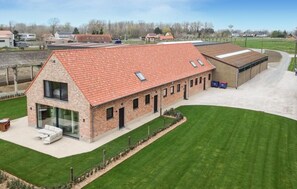 Un grand bâtiment en briques, doté d’un toit en pente, d’un espace extérieur abrité et d’une pelouse bien entretenue.