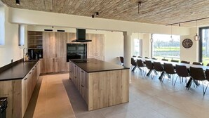 A modern kitchen with a central island, built-in appliances, and a dining area with chairs.