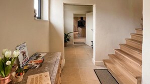 A hallway leading to a kitchen with a wooden staircase.