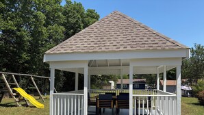 Ein Pavillon mit geneigtem Dach, weißen Geländern und einem Holzboden.