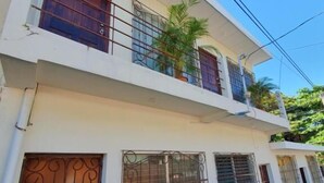 A two-story building with barred windows, a balcony with a potted plant, and a clear sky. - Zacatecoluca House (Zacatecoluca)