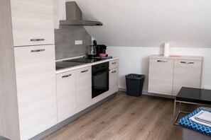 A modern kitchen with a stove, oven, and coffee maker. - Apartment für Monteure (Bad Camberg)