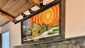 Une cheminée avec un manteau en pierre, un tableau au-dessus et une plante en pot à côté.