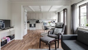 Un salon moderne avec un canapé gris, un fauteuil assorti et un téléviseur posé sur une console blanche.