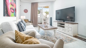 Een moderne woonkamer met een bank, salontafel, televisie en uitzicht op de omgeving.