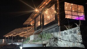 A building with a stone facade, large windows, and string lights. - Complejo Turístico Mixcóatl  (San Martín de las Pirámides)