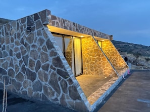 A stone building with a glass door and a yellow-lit interior. - Complejo Turístico Mixcóatl  (San Martín de las Pirámides)