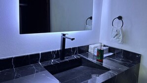A bathroom with a black marble sink, a mirror, and a towel rack with a towel. - Complejo Turístico Mixcóatl  (San Martín de las Pirámides)