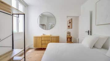 Ein Schlafzimmer mit einem Bett, einem Holzschrank, einem runden Spiegel und einem Fenster.