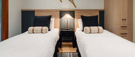 A hotel room with two beds, a nightstand with a lamp, and a wardrobe.