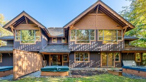 A two-story house with a large deck and a hot tub. - Harmony Chalet at Montebello (Whistler)