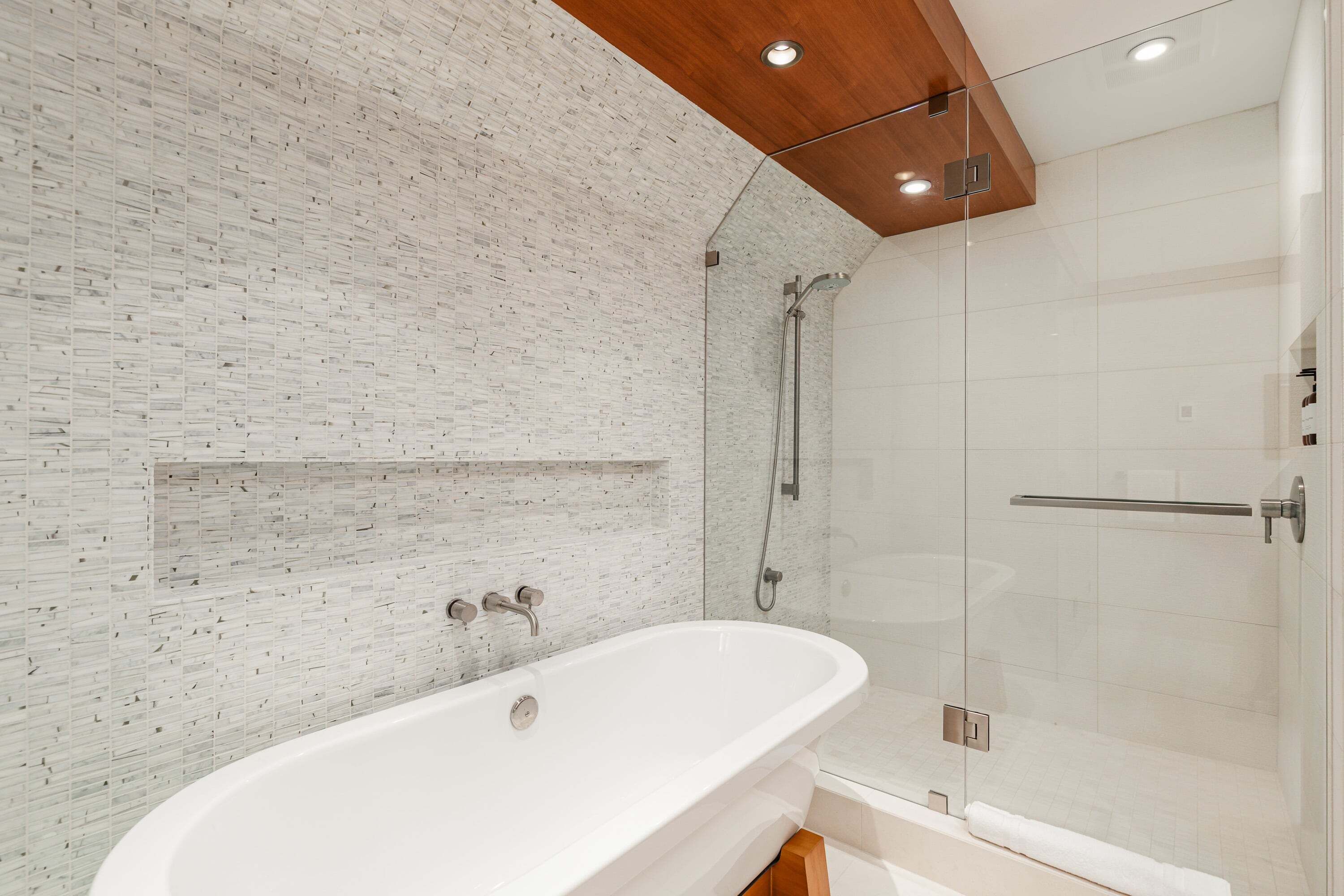A modern bathroom with a freestanding bathtub, a glass-enclosed shower, and a wooden ceiling.