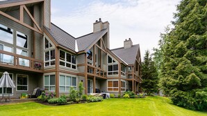 A modern multi-story house with large windows, a balcony, and a well-maintained lawn. - Northlight Retreat at Alpine Greens (Whistler)