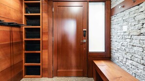 A wooden door with a frosted glass panel, a built-in bench, and a stone wall. - Northlight Retreat at Alpine Greens (Whistler)