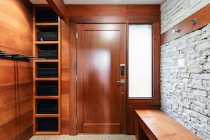 A wooden door with a frosted glass panel, a built-in bench, and a stone wall. - Northlight Retreat at Alpine Greens (Whistler)