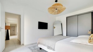Une chambre à coucher moderne, équipée d’un lit, d’une télévision, d’un miroir et d’un ventilateur de plafond.