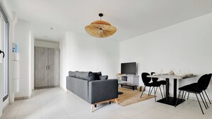 Un salon moderne comprenant un canapé, une table à manger, des chaises et un téléviseur.