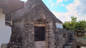 Une construction en pierre surmontée d’un toit conique, dotée d’une fenêtre grillagée et d’une petite porte.