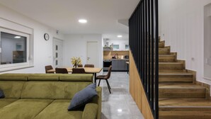 A modern interior with a green sofa, dining table, kitchen, and wooden staircase. - Amazing home in Banfi (Banfi)