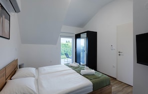 A bedroom with a bed, a balcony, and a door.