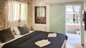 A bedroom with a bed, pillows, a painting, a radiator, and a view of a bathroom. - Awesome home in Slunj with sauna (Slunj)