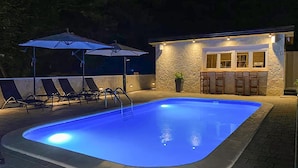 A swimming pool with lounge chairs and umbrellas, a stone wall, and a bar area. - Awesome home in Slunj with sauna (Slunj)