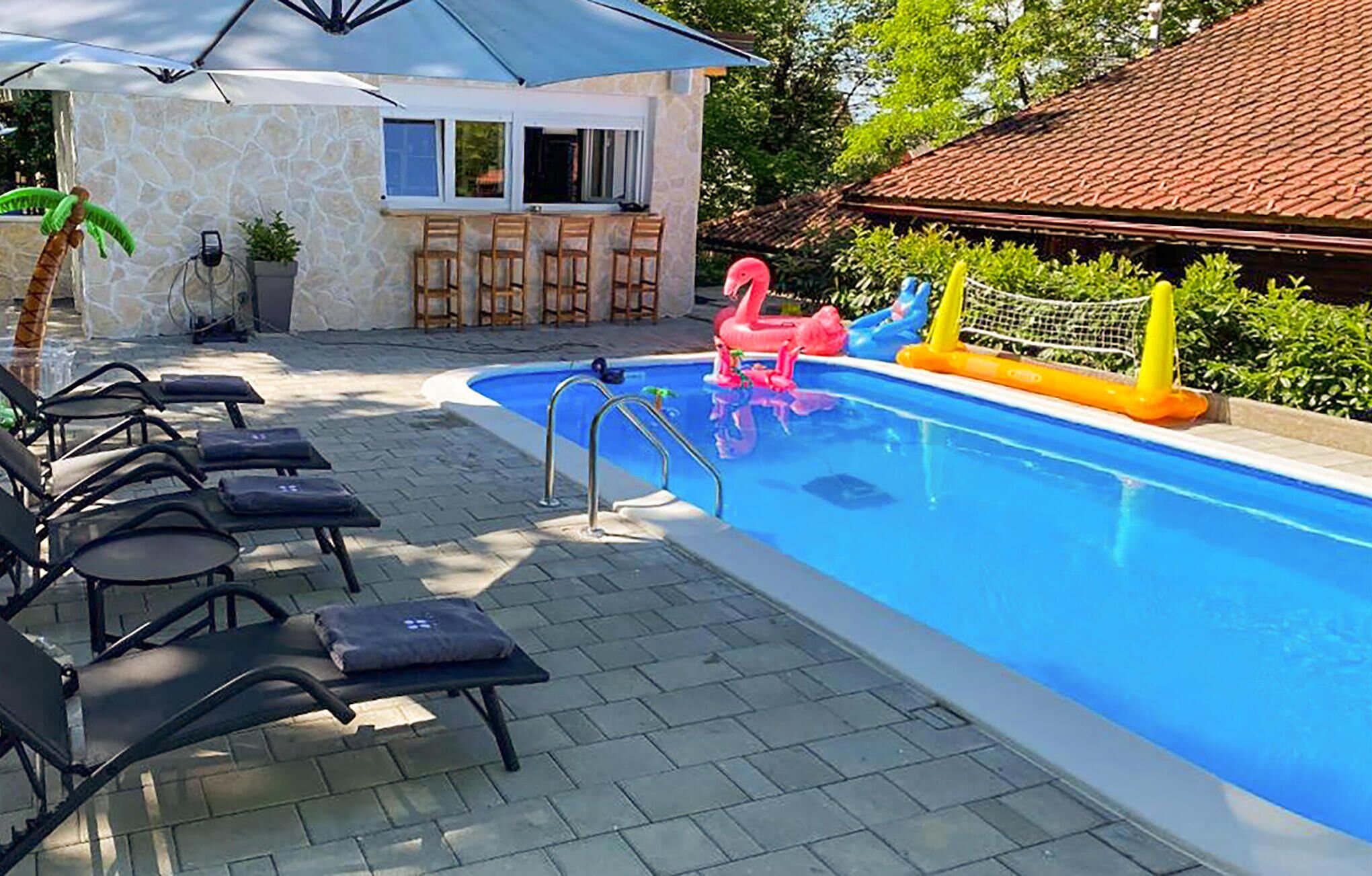 A swimming pool with lounge chairs, a bar area, and a slide.
