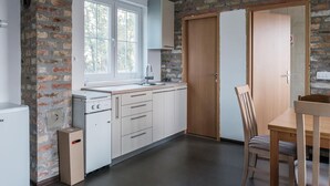 Een keuken met een bakstenen muur, een raam, een spoelbak en een houten eettafel met stoelen.
