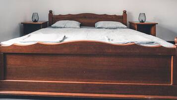 A wooden bed with a headboard, two bedside tables, and a blanket.