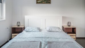 Een slaapkamer met een bed, twee nachtkastjes en een schilderij aan de muur.