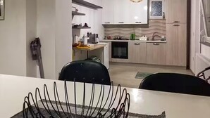 Moderni keittiö, jossa on valkoiset kaapit, sisäänrakennettu uuni ja riippuvalaisin.