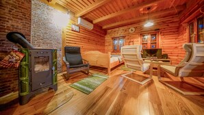 L'intérieur d'une cabane en rondins, avec une cheminée, un téléviseur et un lit.