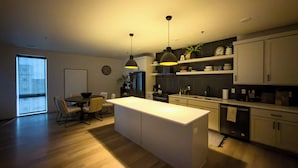 A modern kitchen with a central island, pendant lighting, and a dining area with a table and chairs. - Luxury Condo Downtown Fargo (Fargo)
