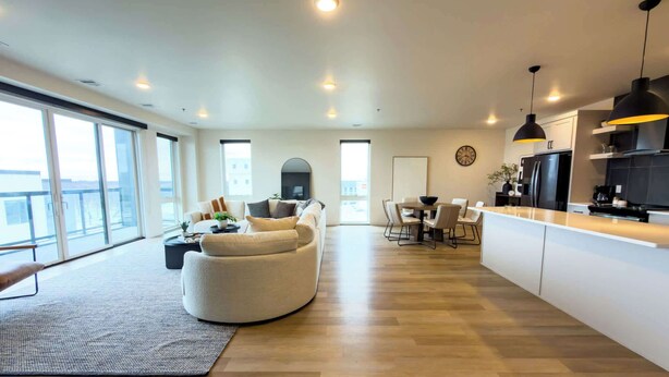 A modern living space with a sofa, dining table, and kitchen area. - Luxury Condo Downtown Fargo (Fargo)