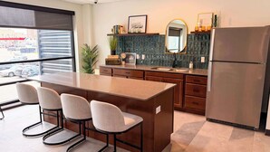 A modern kitchen with a central island, bar stools, a refrigerator, and a window with a view of the street. - Luxury Condo Downtown Fargo (Fargo)
