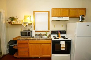 Une cuisine de taille réduite, dotée de meubles en bois, d’un four à micro-ondes, d’une cuisinière et d’un réfrigérateur.