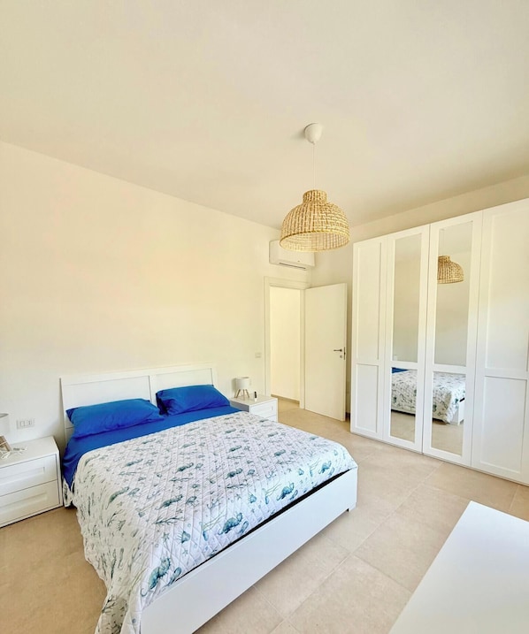 Un dormitorio con cama, armario blanco y lámpara colgante.