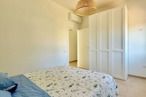 Un dormitorio con cama, armario y lámpara colgante.