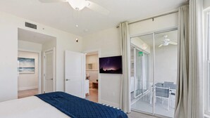 A bedroom with a bed, a ceiling fan, a sliding glass door leading to a balcony, and a night sky painting on the wall. - #1516 - Amazing Golf and Lake View in Luxury Villa (Naples)