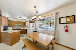 A kitchen with wooden cabinets, a central island, a dining table, and a fire extinguisher on the wall.