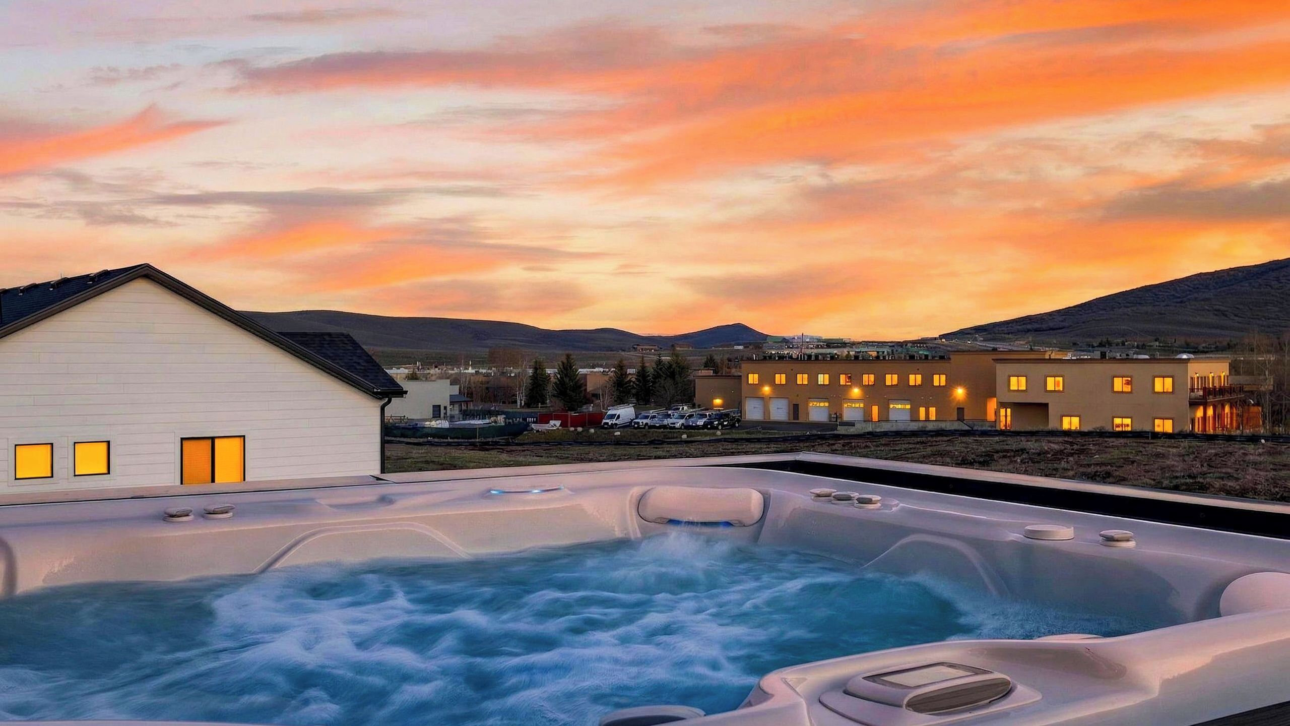 Ein Whirlpool mit Blick auf einen Gebäudekomplex und Berge im Hintergrund.