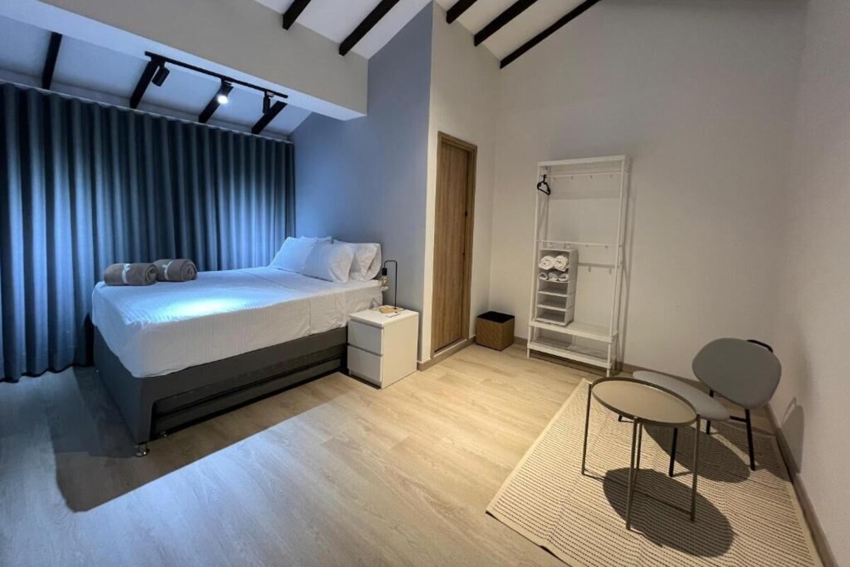 A modern bedroom with a bed, bedside table, and a small seating area with two chairs.