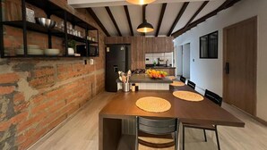 A modern kitchen with a central island, black shelving, and a hanging light fixture. - Apartamento Hija Mía (Medellín)