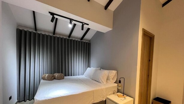 A modern bedroom with a bed, bedside table, and a small trash bin. - Apartamento Hija Mía (Medellín)