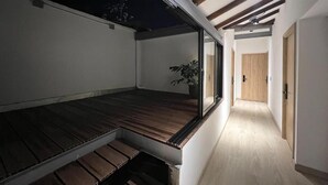 A modern interior with a wooden floor, a sliding glass door, and a hallway leading to a door. - Apartamento Hija Mía (Medellín)